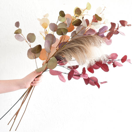 Handpicked silk eucalyptus stems shown loosely, featuring Dusky Ember, Burgundy, and Warm Taupe tones, perfect for DIY projects
