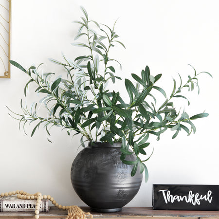 Artificial olive branches styled in a black ceramic vase with a 'Thankful' sign, creating a rustic and cozy atmosphere