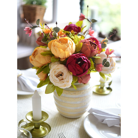 Sunset Whisper silk peony and hydrangea bouquet in a ceramic vase with gold taper candle holders on an elegant dining table.
