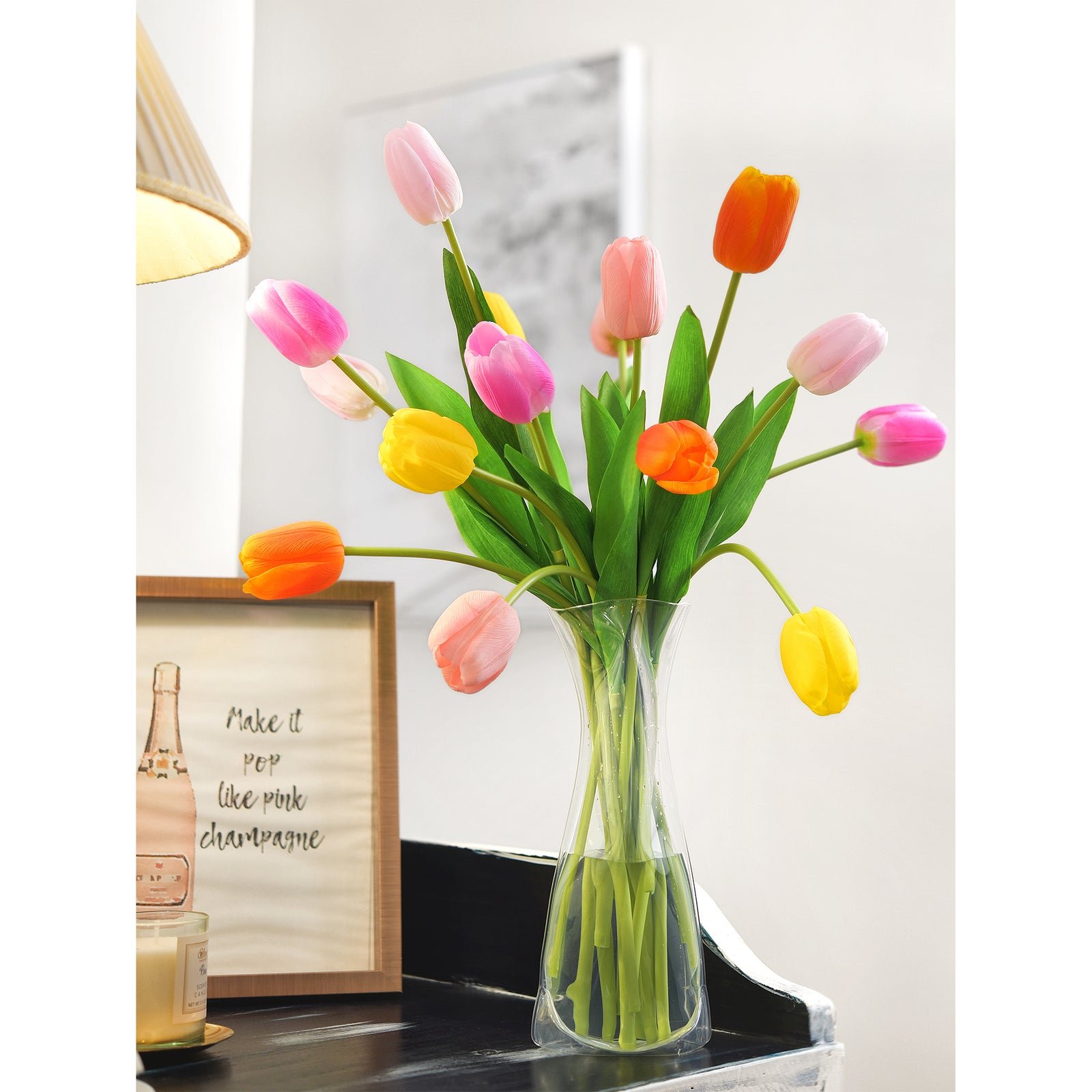 Elegant artificial tulip arrangement in orange, yellow, and pink shades in a clear vase, placed on a modern table with a motivational framed quote for home decor.
