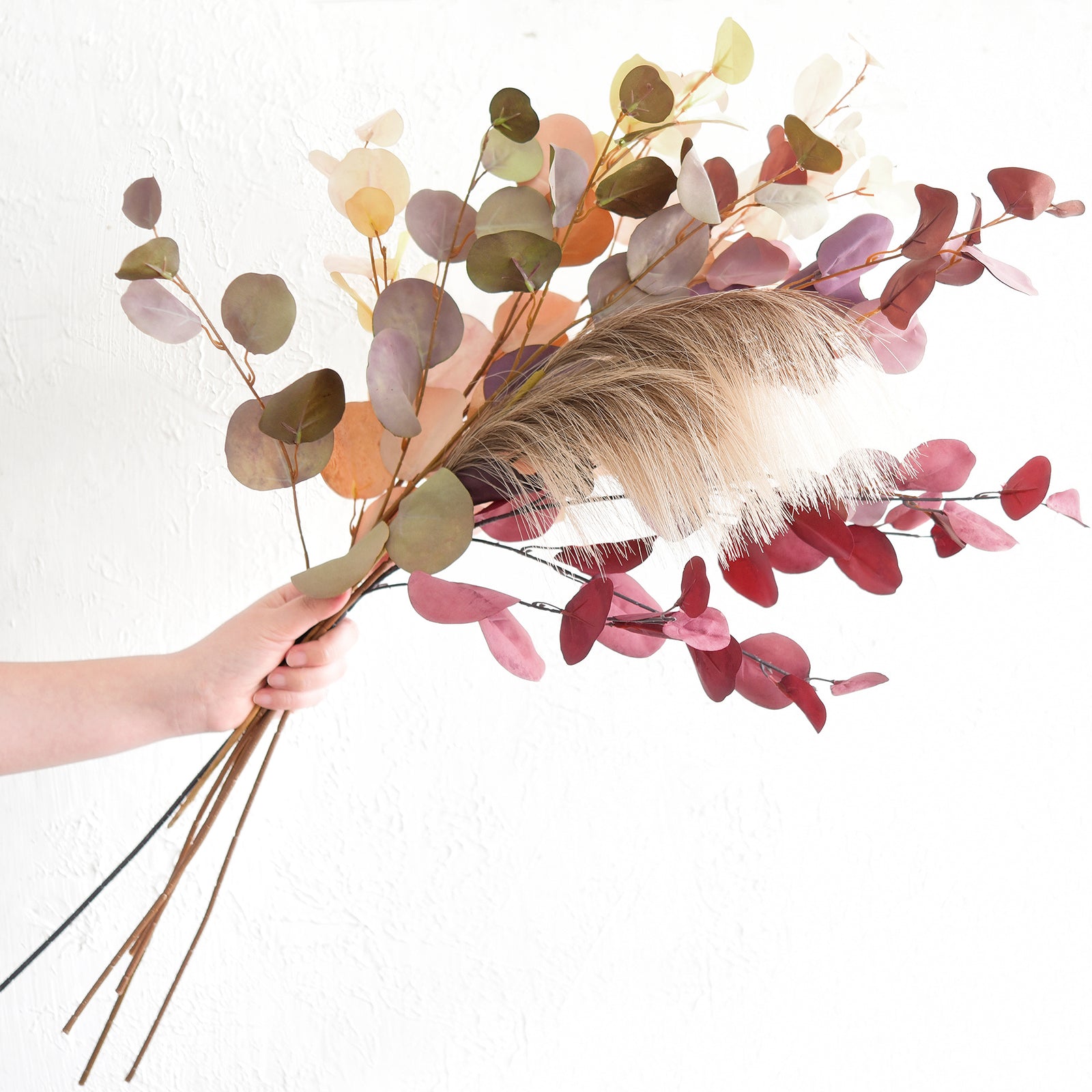 Handpicked silk eucalyptus stems shown loosely, featuring Dusky Ember, Burgundy, and Warm Taupe tones, perfect for DIY projects