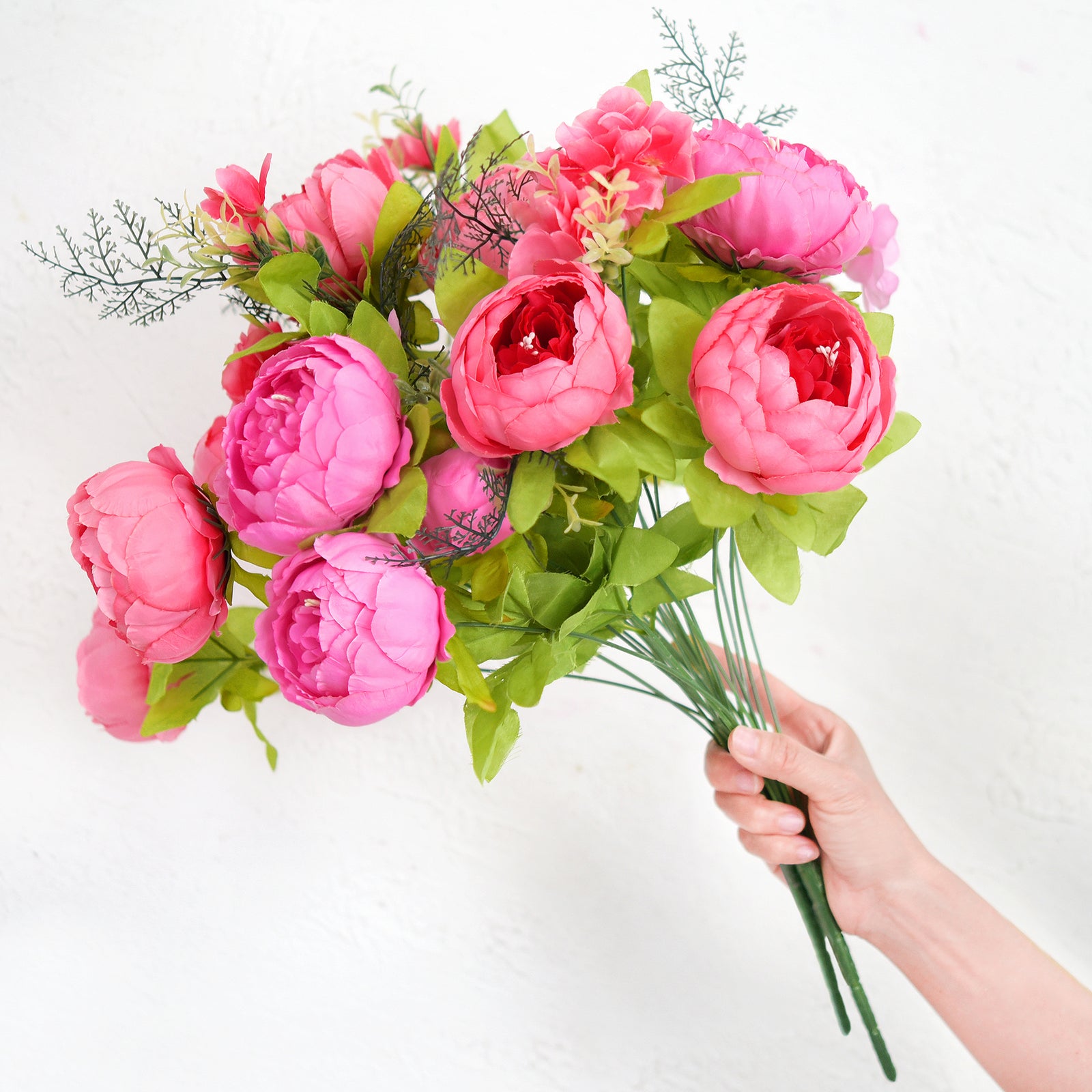 Person holding the full artificial hot pink peony bouquet with bendable stems and lifelike detailing, perfect for arranging in any vase.