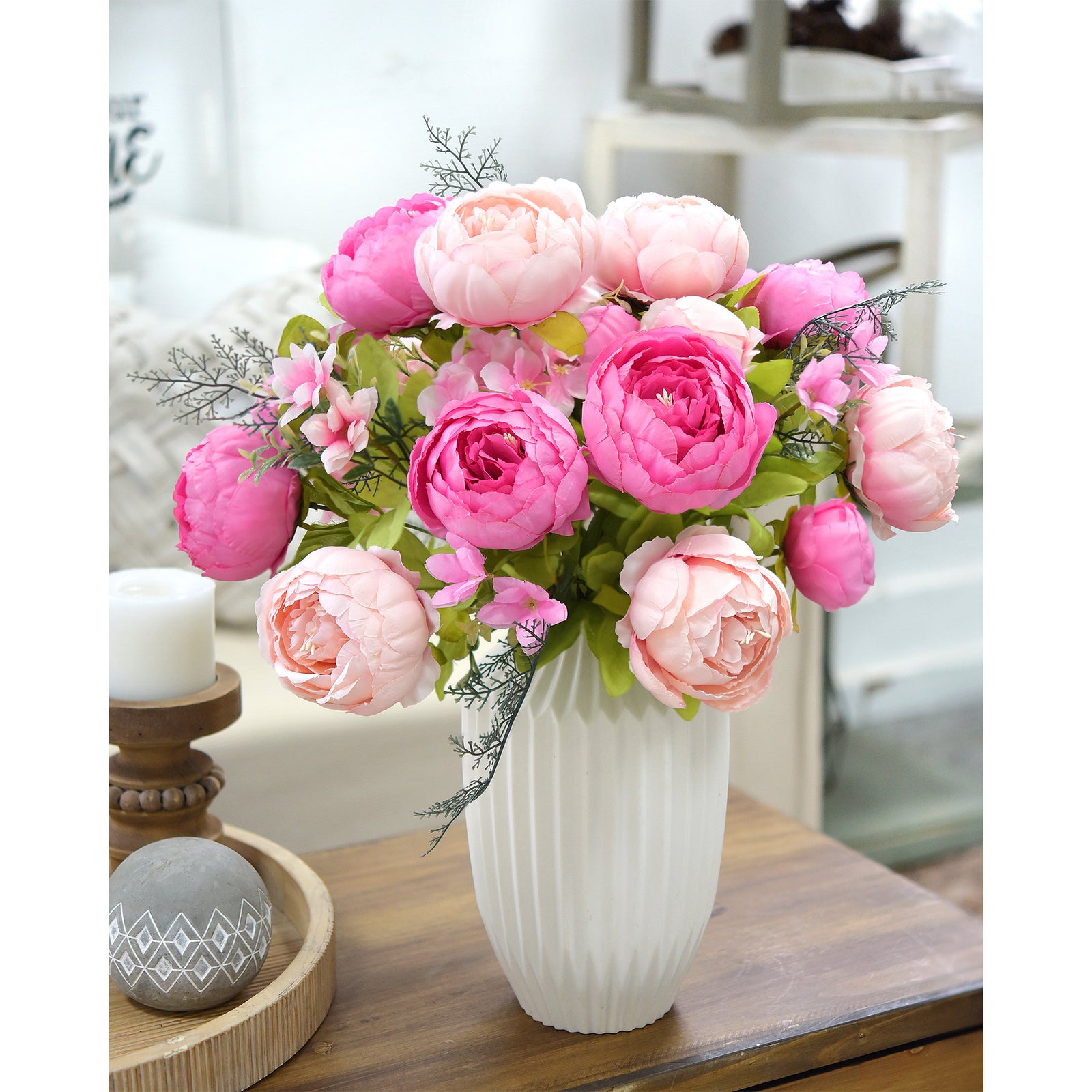 Artificial peony bouquet in bold pink tones set in a ceramic vase, styled with candles and a wooden tray for romantic table decor.