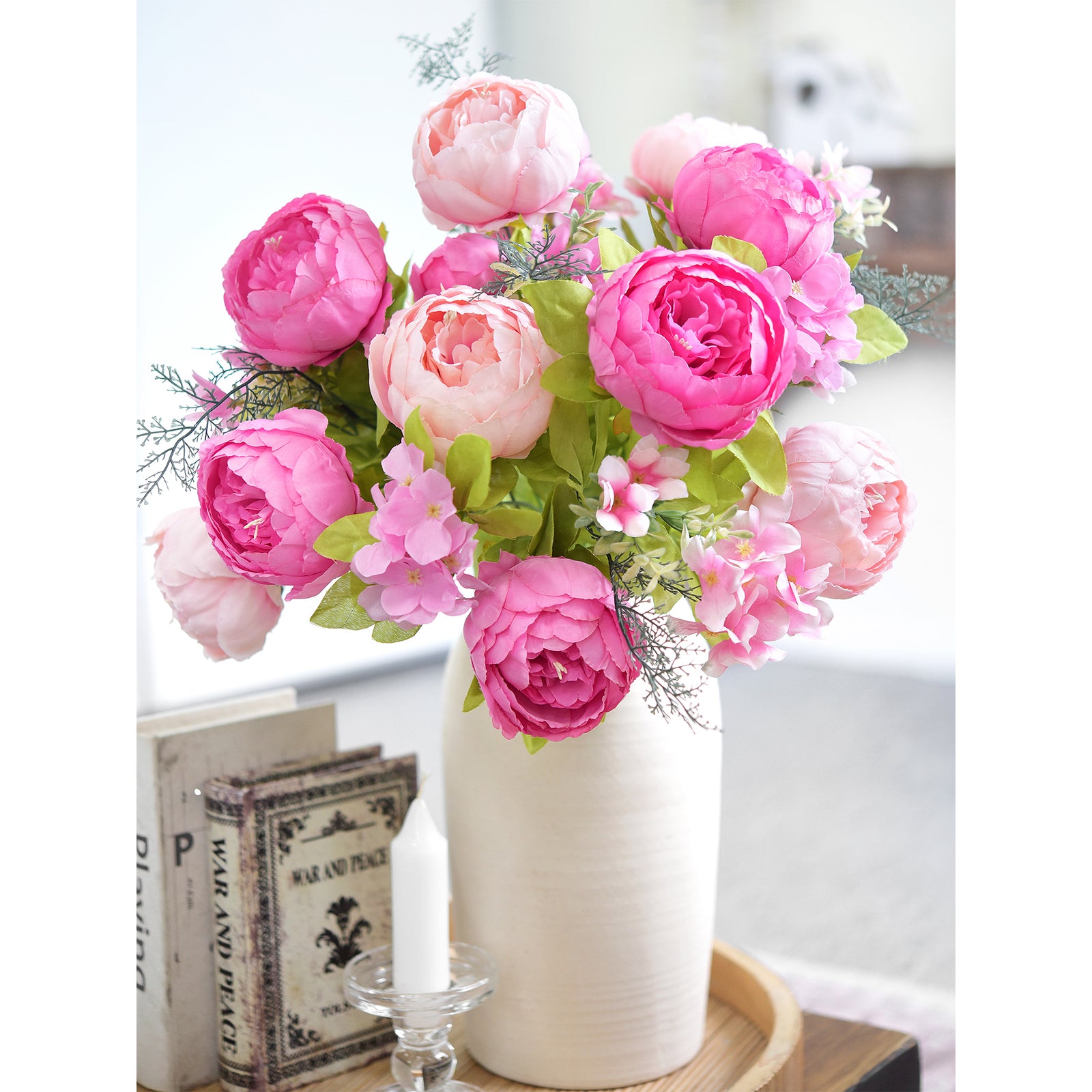 Pink and blush artificial peonies arranged in a white vase, styled on a neutral-tone table with vintage accents and soft lighting.