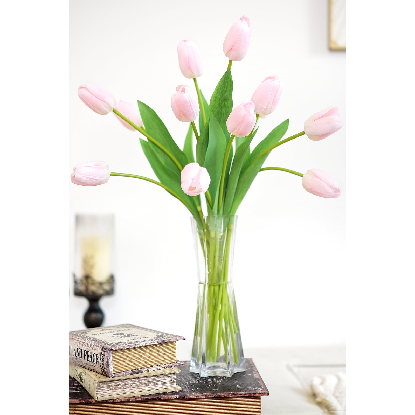 Lifelike artificial pink tulip arrangement in a pvc vase, placed on a vintage book stack for décor inspiration