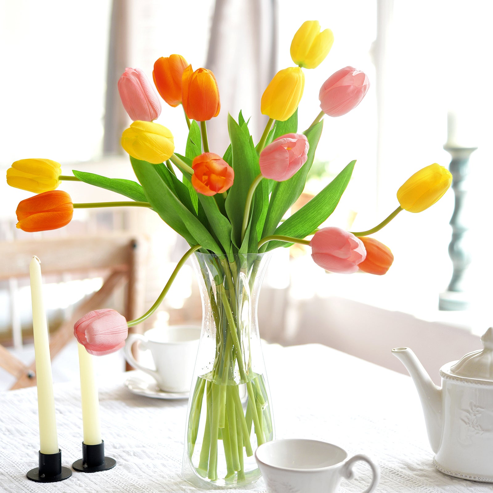 Real touch tulips in a clear vase on a sunny dining table for cheerful spring décor.
