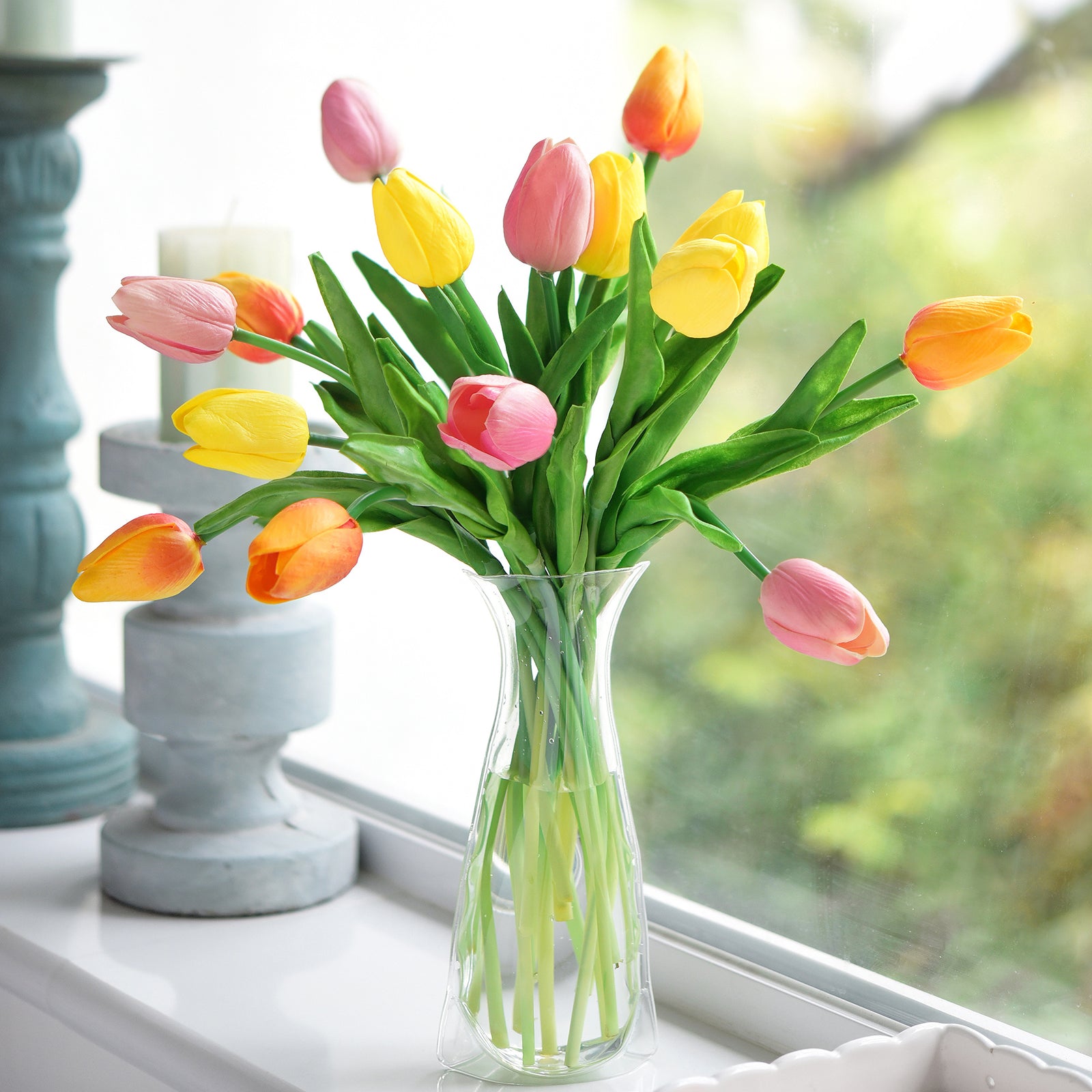 Vibrant spring tulip arrangement placed on a sunny windowsill, showcasing the realistic texture and lively hues of orange, yellow, and pink.
