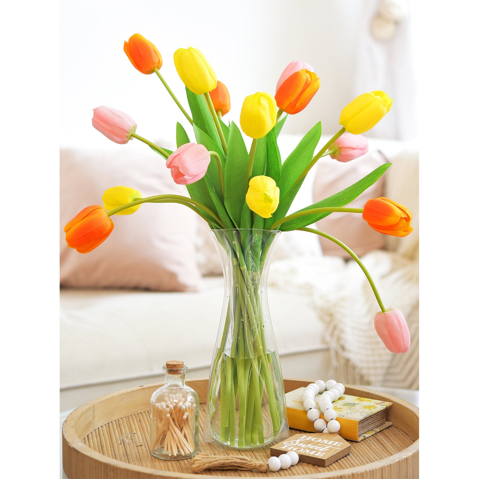 Vibrant artificial tulips in orange, yellow, and pink displayed in a vase on a cozy living room table.
