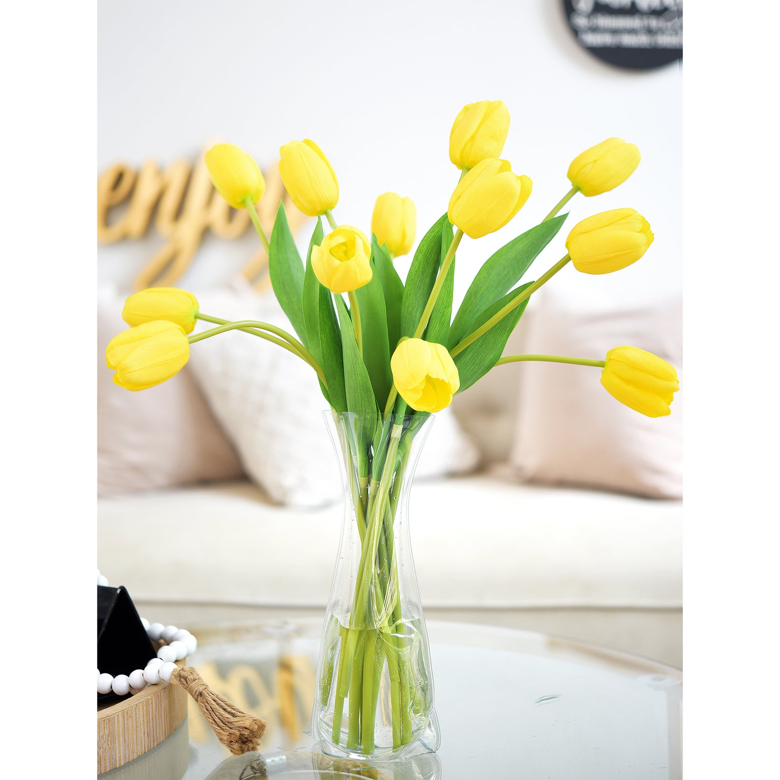 Vibrant artificial yellow tulips displayed in a tall vase on a coffee table in a cozy living room.